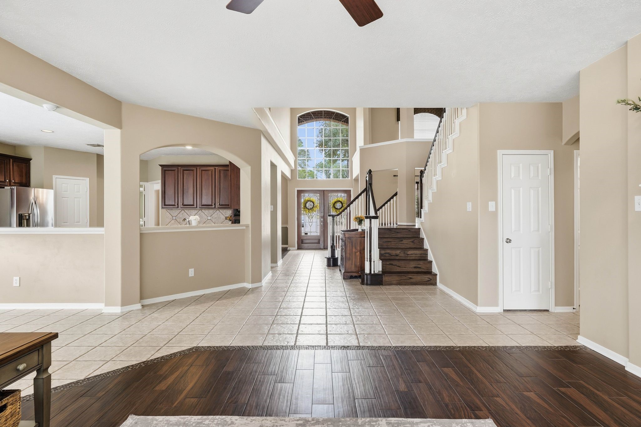 2515 Woodsboro Drive Spring, TX 77388 - Photo 9 of 44 This spacious entryway features a mix of tile and wood tile flooring, with an open view of the staircase and high ceilings. The kitchen has modern stainless steel appliances and rich wood cabinetry, creating a warm and inviting space. Large windows allow plenty of natural light.