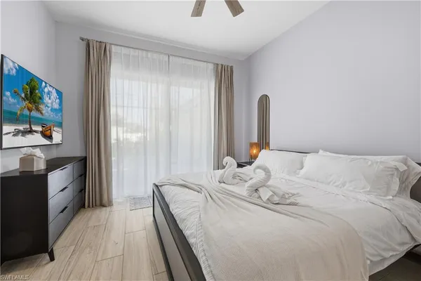 a bedroom with a bed and a flat tv screen on dresser