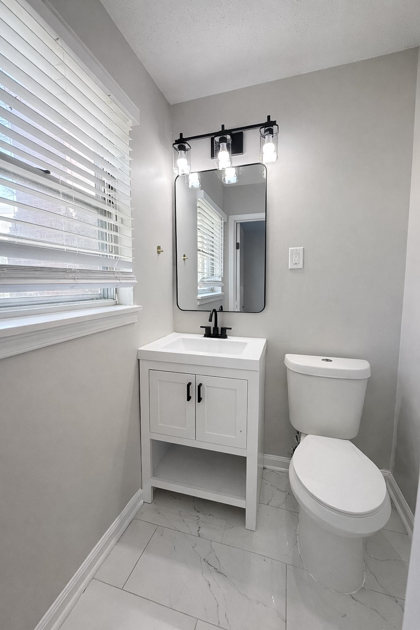 4174 Hobson Road Memphis, TN 38128 - Photo 16 of 24 Half bath featuring vanity, light marble finish flooring, and a textured ceiling