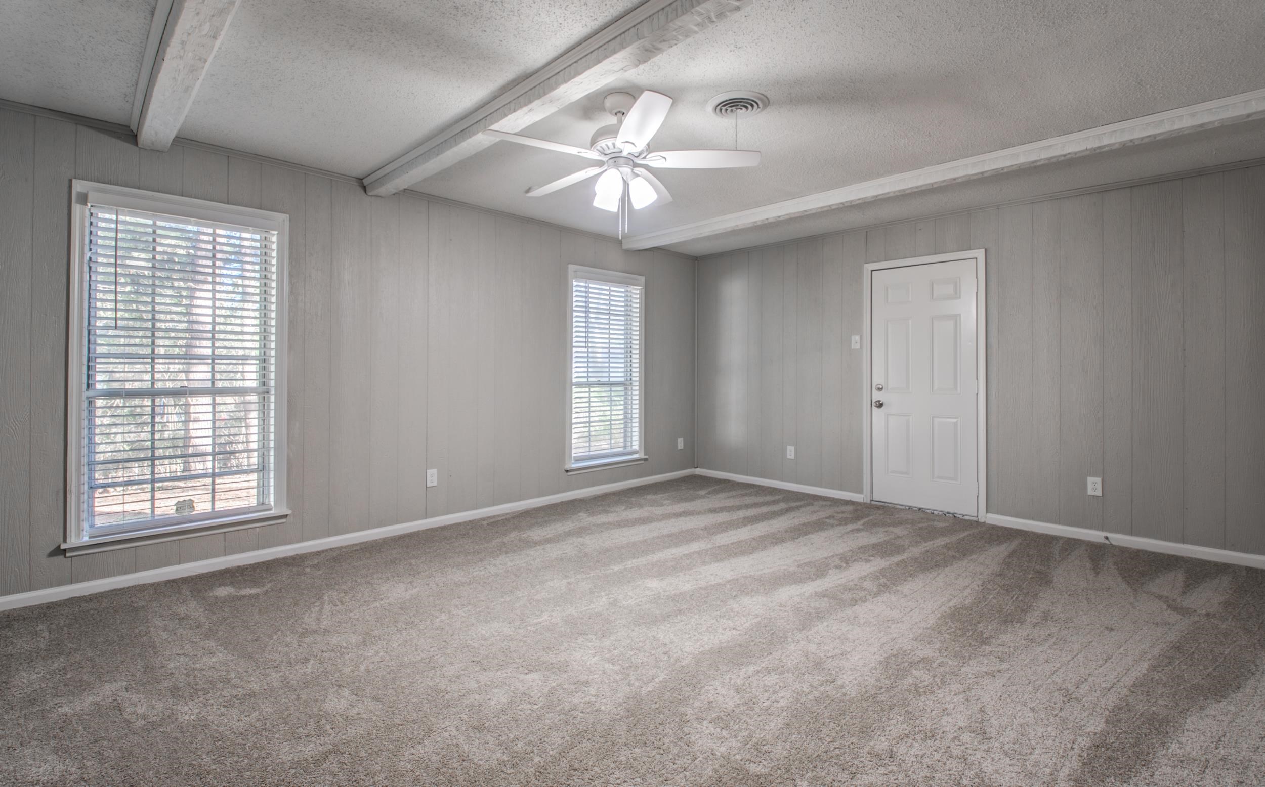 4174 Hobson Road Memphis, TN 38128 - Photo 9 of 24 Carpeted empty room featuring a textured ceiling, a ceiling fan, beamed ceiling, and wooden walls