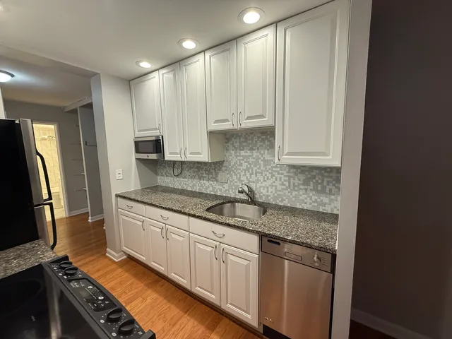 a kitchen with granite countertop a sink stove and refrigerator