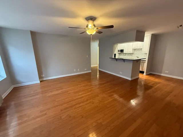 a view of an empty room with wooden floor and a chandelier