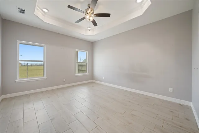 an empty room with windows and ceiling fan