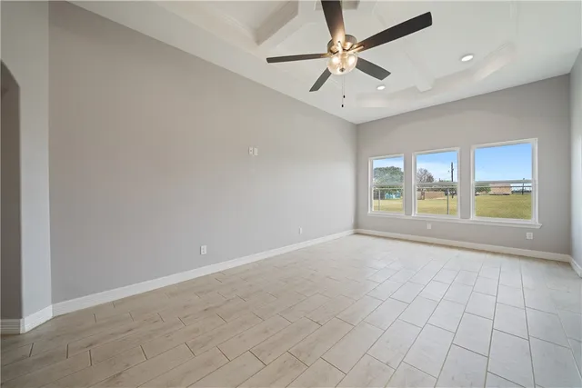 an empty room with chandelier fan and windows
