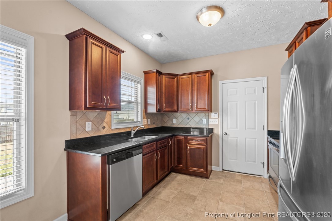 43 Battery Way Bunnlevel, NC 28323 - Photo 24 of 50 a kitchen with stainless steel appliances granite countertop a refrigerator a sink dishwasher and wooden cabinets with wooden floor