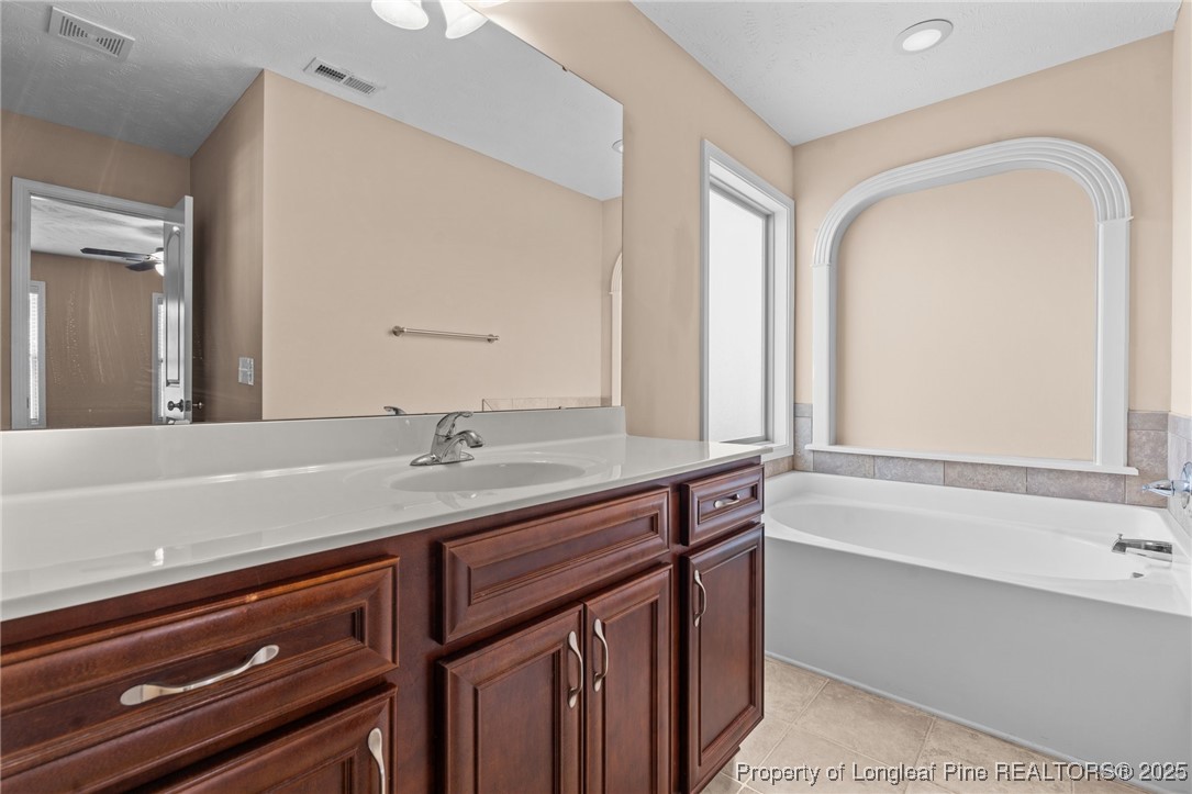 43 Battery Way Bunnlevel, NC 28323 - Photo 42 of 50 a bathroom with a granite countertop sink a large mirror a vanity and a bathtub