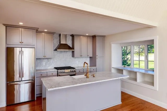 a kitchen with stainless steel appliances granite countertop a sink a stove a refrigerator and island with wooden floor