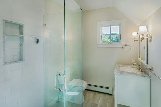a bathroom with a granite countertop sink a toilet and shower
