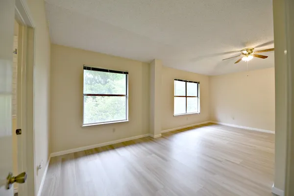 an empty room with wooden floor and windows