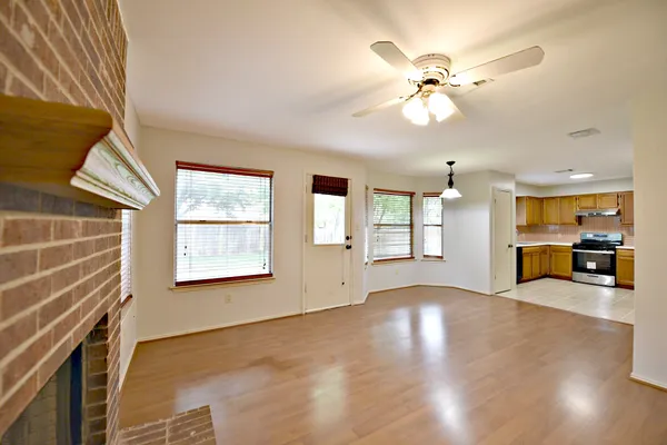a view of an empty room with a window and wooden floor