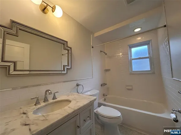 a bathroom with a granite countertop sink a toilet and a mirror