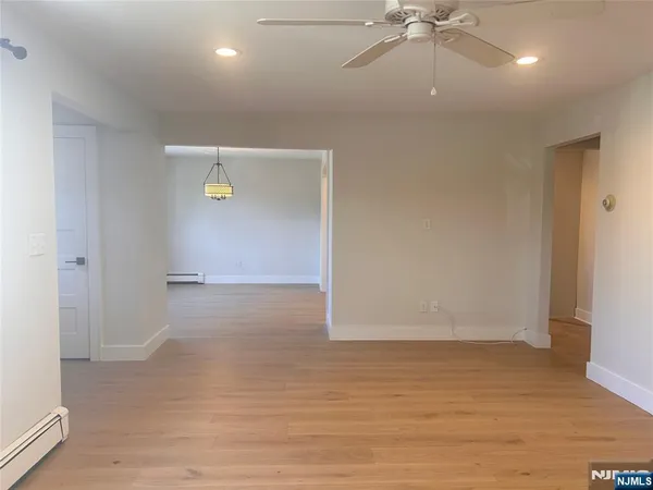 an empty room with wooden floor and fan