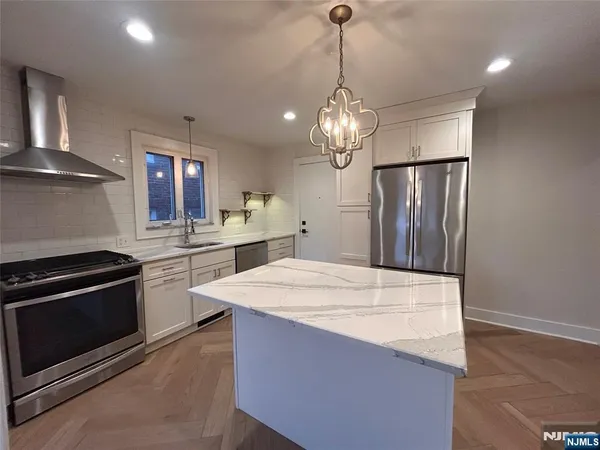 a kitchen with stainless steel appliances a stove refrigerator and cabinets