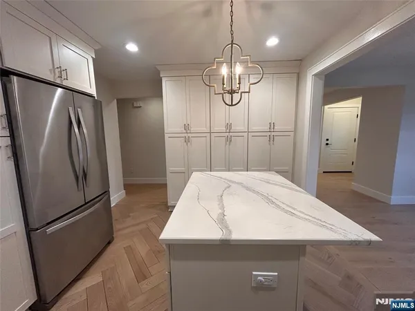 a kitchen with stainless steel appliances a refrigerator a sink cabinets and wooden floor