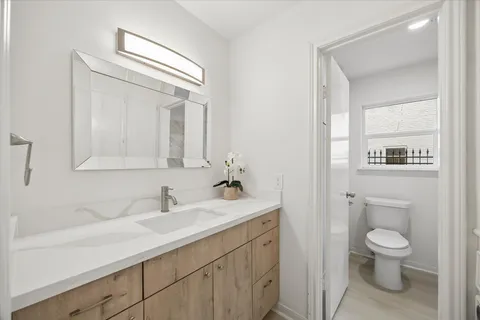a bathroom with a toilet a sink a mirror and vanity