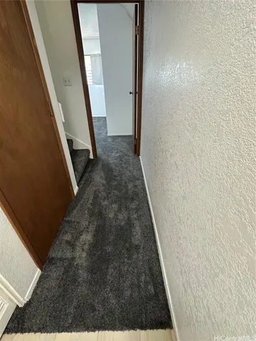 a view of a hallway with wooden floor and a bathroom