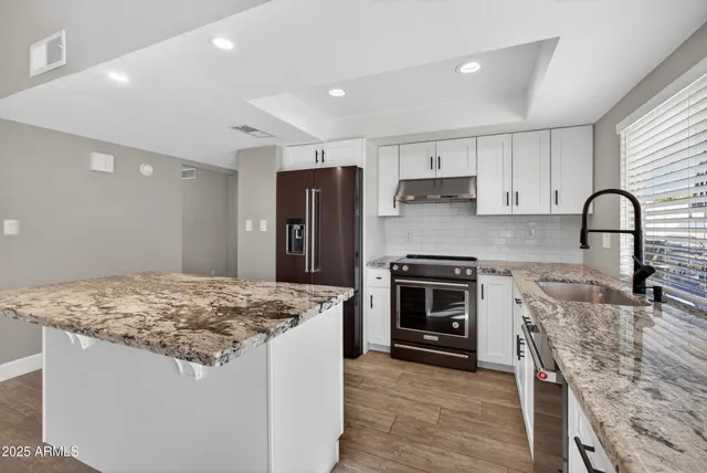 a kitchen with stainless steel appliances granite countertop a stove refrigerator sink and microwave