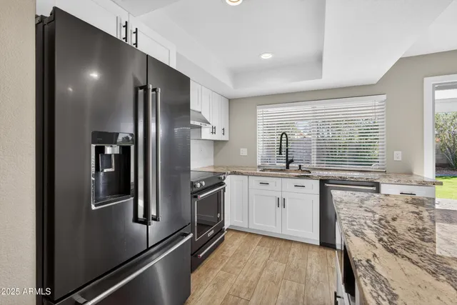 a kitchen with granite countertop stainless steel appliances a refrigerator stove top oven and sink