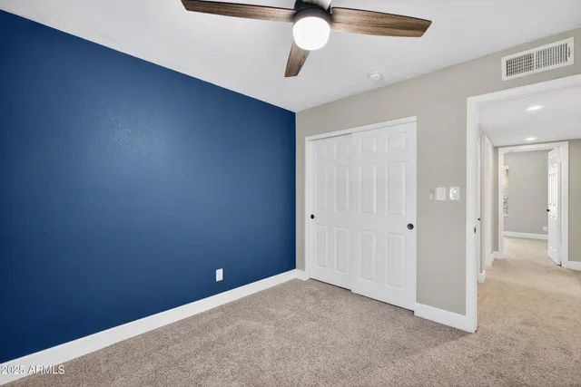 an empty room with a ceiling fan and carpet