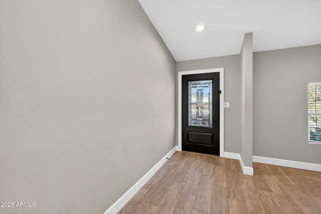a view of an empty room with window and wooden floor