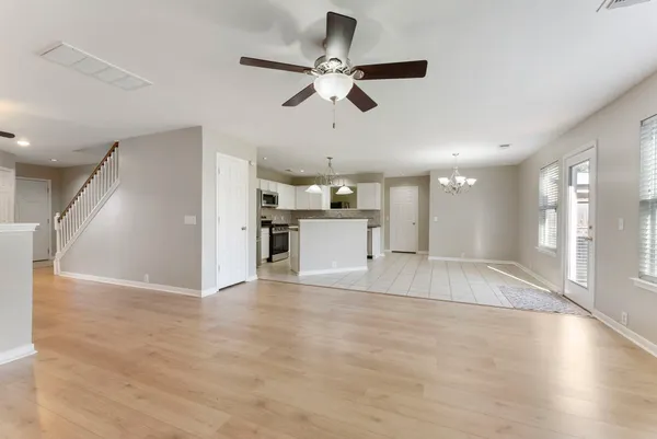 a view of an empty room with wooden floor and a ceiling fan