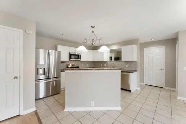 a kitchen with granite countertop a refrigerator and a stove top oven