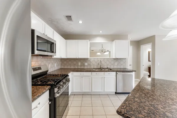 a kitchen with stainless steel appliances granite countertop a stove top oven a sink a microwave and a refrigerator