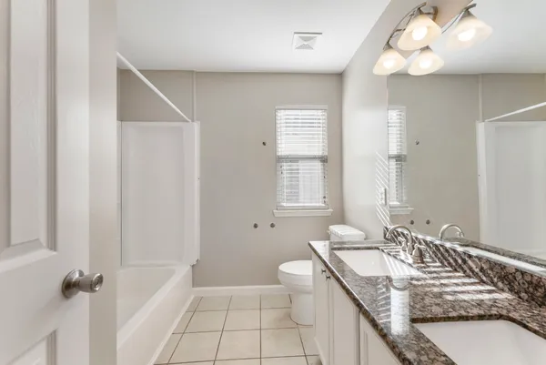 a bathroom with a granite countertop sink a toilet and a mirror
