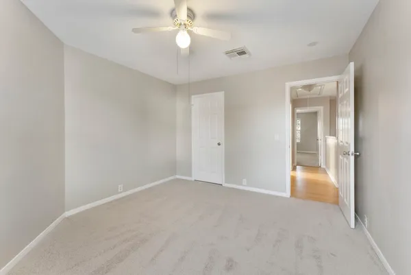 a view of an empty room with a chandelier fan