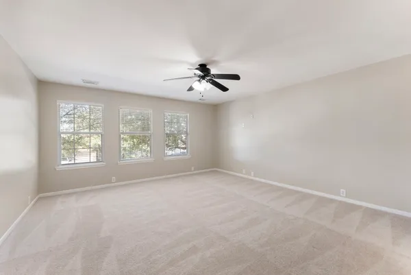 an empty room with windows and chandelier fan