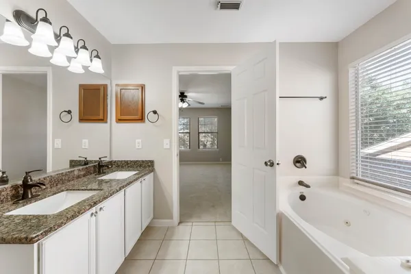 a bathroom with a granite countertop sink a mirror a bathtub and shower