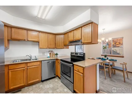 a kitchen with stainless steel appliances granite countertop wooden cabinets a sink a stove a dining table and chairs