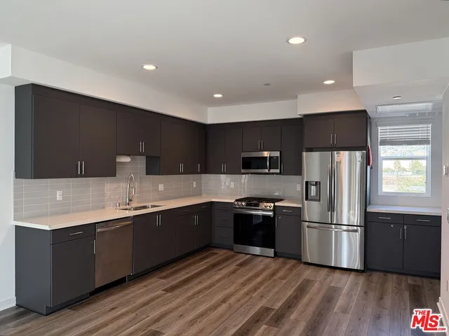 a kitchen with stainless steel appliances granite countertop a sink a stove a refrigerator and cabinets