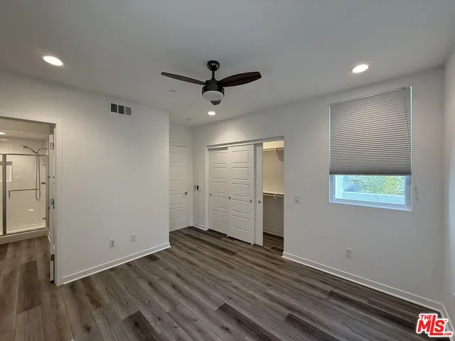 an empty room with wooden floor a ceiling fan and windows