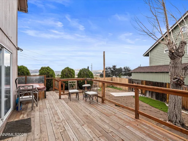 a view of a roof deck with table and chairs a barbeque with wooden floor and fence