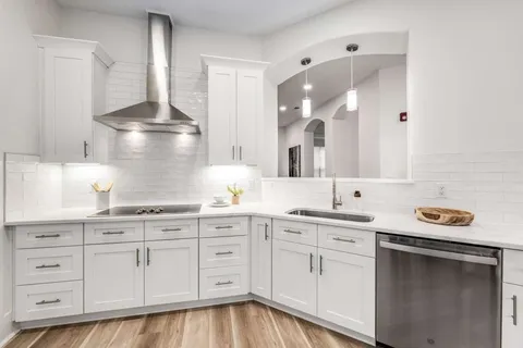 a kitchen with white cabinets and sink
