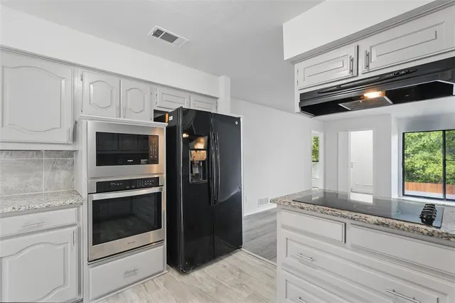 a kitchen with stainless steel appliances granite countertop a sink a stove and cabinets
