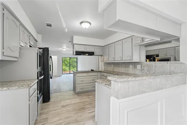 a kitchen with stainless steel appliances granite countertop a refrigerator a stove and a sink