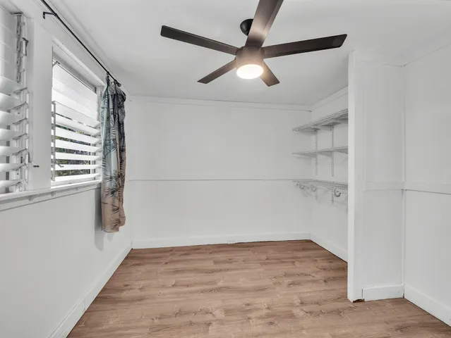 a view of empty room with wooden floor and fan