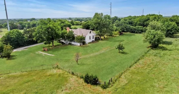 an aerial view of residential house with outdoor space and trees all around