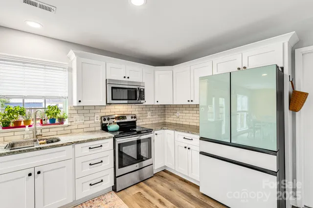 a kitchen with white cabinets stainless steel appliances and a window