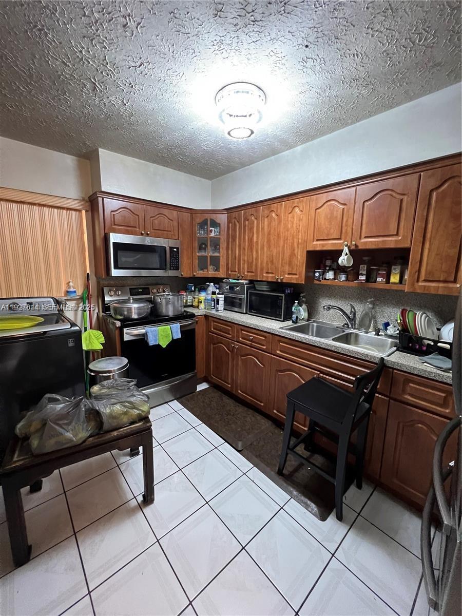 1581 Northeast 117th Street Miami, FL 33161 - Photo 19 of 29 a kitchen with stainless steel appliances a stove a sink dishwasher and cabinets with wooden floor