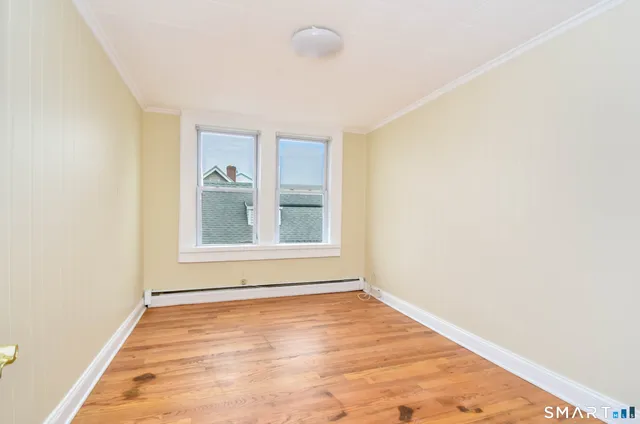 a view of an empty room with wooden floor and a window