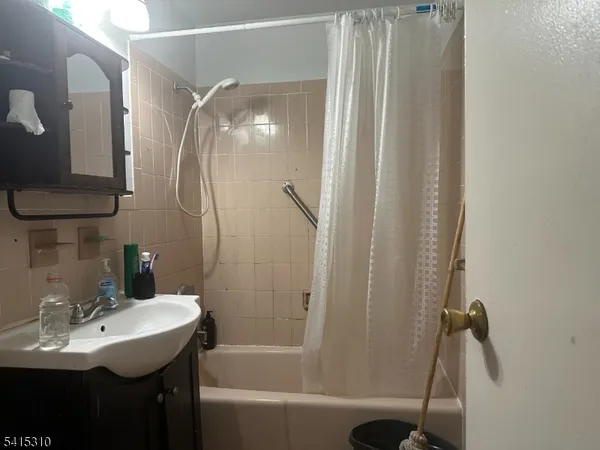 a bathroom with a sink and mirror with bathtub