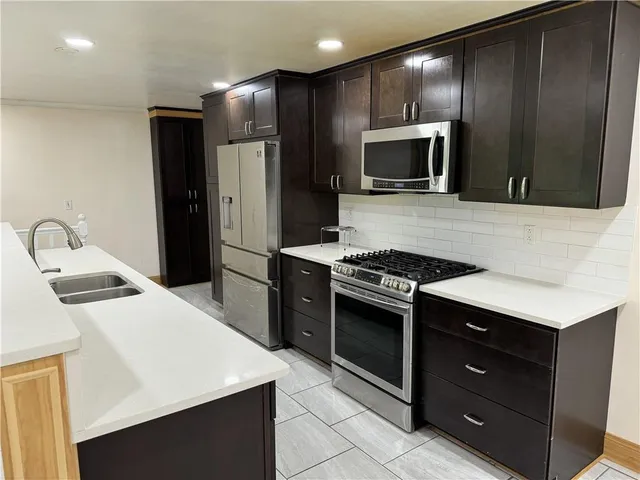 a kitchen with stainless steel appliances kitchen island granite countertop a refrigerator stove and sink