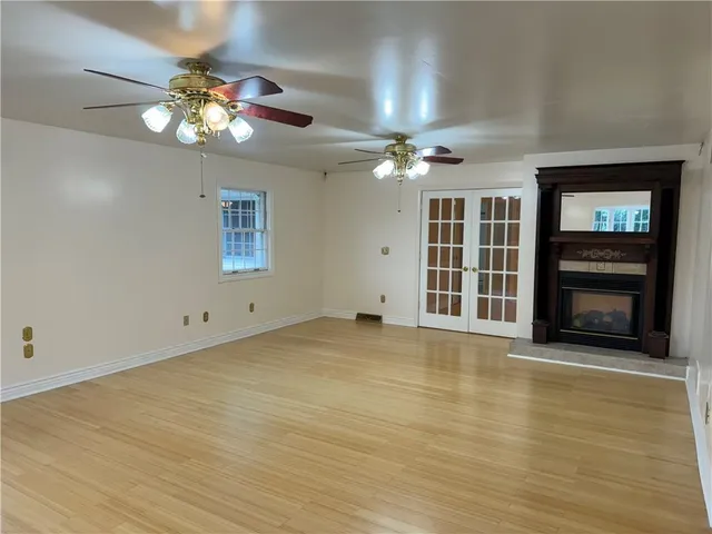 a view of an empty room with a fireplace and chandelier fan