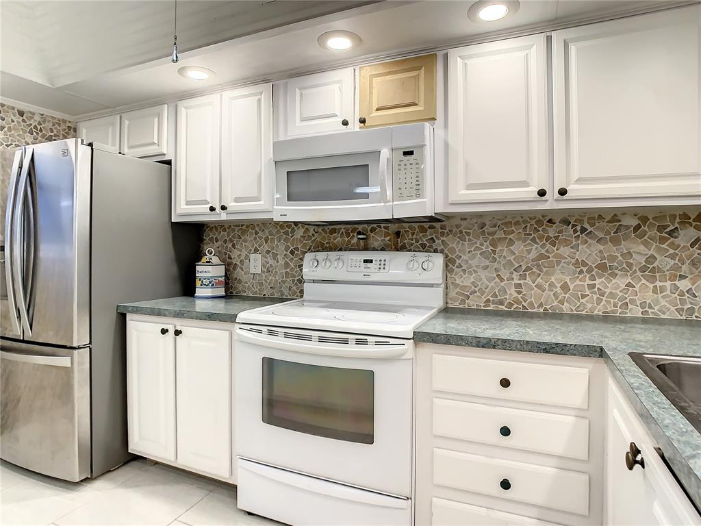 18304 Gulf Boulevard, Unit 116 Redington Shores, FL 33708 - Photo 12 of 51 a kitchen with white cabinets and white appliances