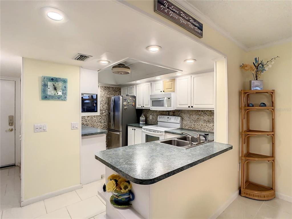 18304 Gulf Boulevard, Unit 116 Redington Shores, FL 33708 - Photo 18 of 51 a kitchen with stainless steel appliances granite countertop a sink a refrigerator and a stove