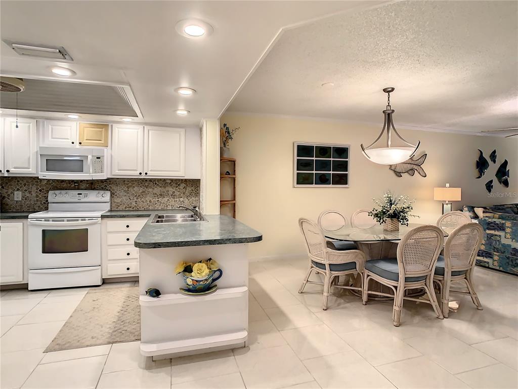18304 Gulf Boulevard, Unit 116 Redington Shores, FL 33708 - Photo 9 of 51 a kitchen with stainless steel appliances kitchen island granite countertop a table and chairs in it