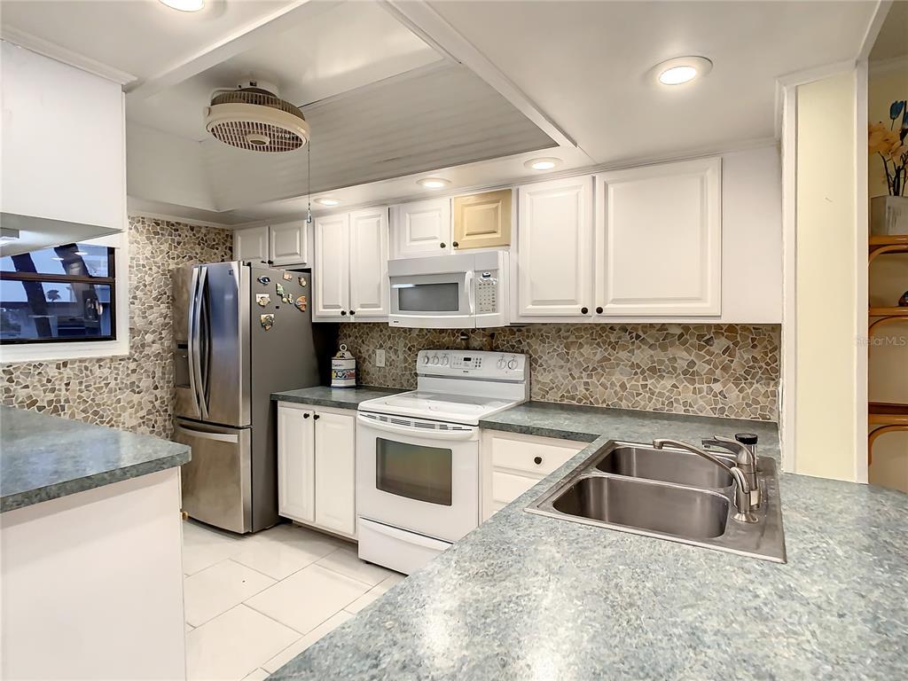 18304 Gulf Boulevard, Unit 116 Redington Shores, FL 33708 - Photo 10 of 51 a kitchen with a sink cabinets and stainless steel appliances